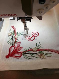 a sewing machine is working on a white towel with red and green embroidered letters that spell out the letter e