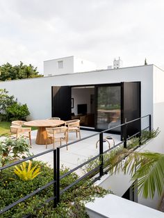 an outdoor dining area with table and chairs on the deck, surrounded by greenery