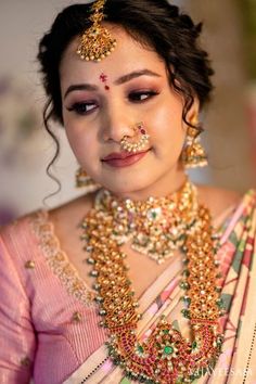 a woman in a pink sari with gold jewelry on her neck and nose ring