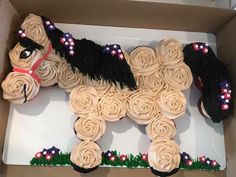 a cupcake shaped like a horse is in a box with grass and flowers on it