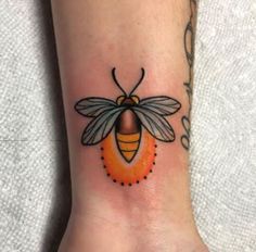 a small bee tattoo on the wrist is shown in black and orange colors, with dots around it