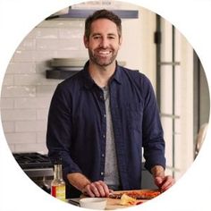 a man standing in front of a cutting board with food on it and smiling at the camera