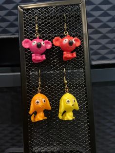 three little toy animals hanging from hooks on a rack in front of a black wall