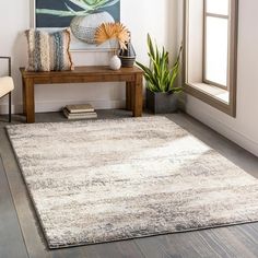 a living room area with a rug, table and chair next to a painting on the wall