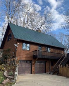 a large brown house with two garages on the front and second story, surrounded by trees