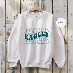 Eagles Shirt School Mascot Shirt Football Mom Shirt Distressed Team Spirit Tee Game Day Sport Spirit Shirt Gameday Apparel 4th of July Shirt  ORDERING: 1. Review all photos 2. Choose Size and Color from drop-down menu 3. If personalization box is available, add your text color 4. Add each shirt to cart one at a time 5. Click "Add to Cart" - you can go back to add more products 6. Click "Proceed to Checkout" 7. Add note to seller for any requests BULK DISCOUNTS AND SPECIAL REQUESTS: We offer bulk School Spirit Shirt With Graphic Print, School Spirit Graphic Print Relaxed Shirt, School Spirit Graphic Print Relaxed Fit Shirt, Fall College Shirt With Graphic Print, White Long Sleeve School Spirit Shirt, White Long Sleeve Shirt For School Spirit, White Relaxed Fit Shirt With Team Name, Relaxed Fit White Shirt With Team Name, Crew Neck Shirt With Lettering In Relaxed Fit