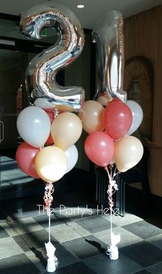 two balloons with the number 2 on them are in front of a black and white checkered floor