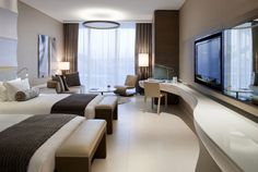 a hotel room with two beds, desk and television