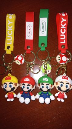 four keychains with mario and luigi on them are sitting on a wooden table