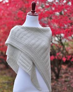 a white knitted shawl on a mannequin in front of trees with red leaves