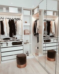 a walk in closet with mirrored walls and white drawers, clothes hanging on hangers