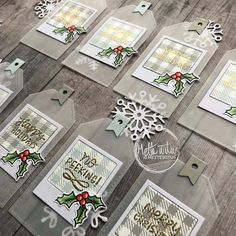 some christmas cards on a table with tags and snowflakes in the background