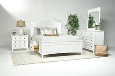 a bedroom with white furniture and plants on the nightstands in front of the bed