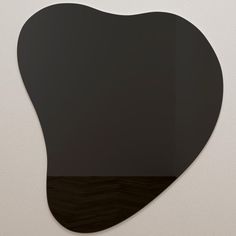 a black heart shaped mirror hanging on the wall next to a white wall and floor