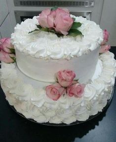 a three layer cake with white frosting and pink flowers