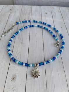 This pretty choker necklace has some sparkle! It's dainty and light weight and is created with aqua, sapphire, blue and white seed beads and a dangle silver sun charm. Perfect for layering with other necklaces - or by itself - so versatile!  Each piece is an original design! COLORS: Aqua Sapphire Blue White Silver MATERIALS Seed beads   Silver sun charm I use a mixture of sterling silver, silver filled, silver plated and stainless steel for the silver beads and clasps. 49 Strand nylon coated wire, flexible and strong SIZE: This choker measures 17 inches with an extender chain to 18 1/2 inches CARE: I use only quality materials which makes this perfect for everyday use.  Can be wiped clean with a dry cloth. I like to use a microfiber cloth. Questions are always welcome! Free shipping I ship Dainty Blue Necklaces For Summer, Blue Spiritual Jewelry For Summer, Spiritual Blue Jewelry For Summer, Blue Dainty Beaded Choker Necklace, Dainty Blue Beaded Choker Necklace, Blue Summer Choker As A Gift, Blue Choker As Summer Gift, Summer Blue Choker As Gift, Dainty Handmade Blue Beaded Necklace