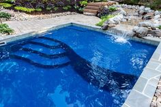 a blue swimming pool surrounded by rocks and plants