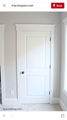 an empty room with a white door and carpet on the floor in front of it