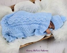 a baby doll is wrapped in a blue knitted blanket on top of a basket