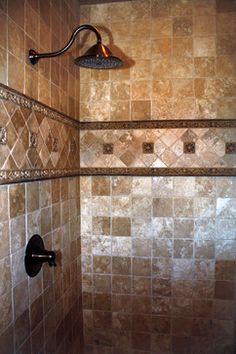 a shower head and hand shower in a tiled bathroom with brown tiles on the walls