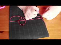 a person is making something out of black paper with red string and scissors on the table