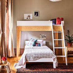 a bedroom with a bunk bed, ladder and rugs on the hardwood flooring