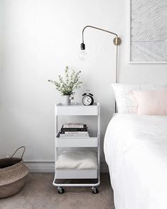 a bedroom with a bed, nightstand and plant on the end table in front of it