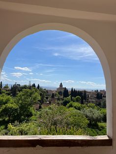 an arched window looking out at the city and trees in the foreground, with blue skies above