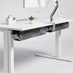 a white desk with a monitor, keyboard and plant on the table next to it