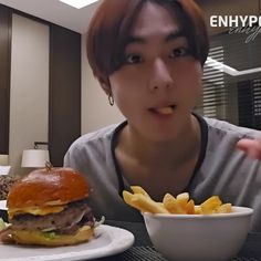 a person sitting at a table with a hamburger and french fries in front of them