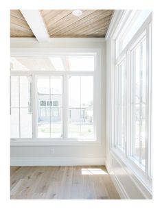 an empty room with wooden floors and white walls, windows in the ceiling and wood paneling