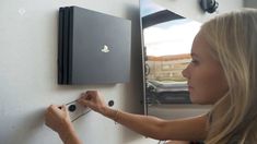 a woman is trying to open the door on a wall mounted video game system that's in front of her