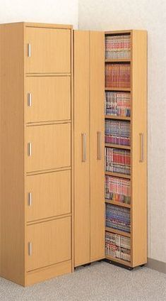 a tall cabinet with several books in it next to a wall mounted bookcase that is open