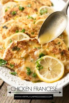 a white plate topped with chicken covered in sauce and lemon slices next to a spoon