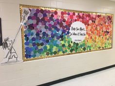 a colorful bulletin board on the wall in a school hallway with an art piece next to it