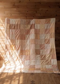 an old quilt is sitting on the floor in front of a wooden paneled wall