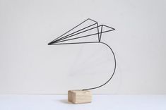 a sculpture made out of wood and wire with a paper airplane on it's head