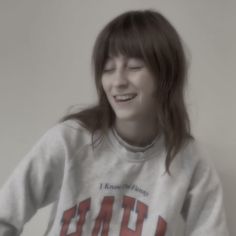 a girl with long hair smiling and wearing a sweatshirt