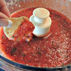 someone is adding sauce in a food processor to make pizzas and other foodstuffs