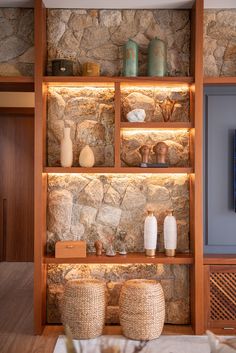 a stone wall with vases and other items on it in front of a flat screen tv