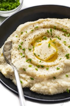 mashed potatoes with olive oil and parsley in a black bowl on a white table