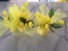 two yellow flowers with green leaves on a marble table