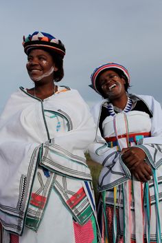 two women with painted faces are standing next to each other in traditional dress and headgear