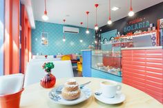 a table with two plates of food and cups on it in front of a colorful wall