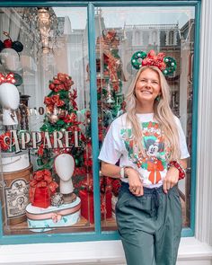 a woman standing in front of a store window with christmas decorations on the windowsill