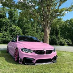 a pink car parked next to a tree