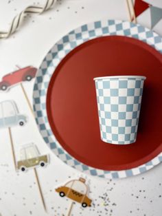 a checkered paper cup sitting on top of a red plate with toothpicks