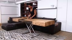 a woman standing in front of a table with two chairs and a couch next to it