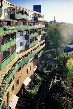 an apartment building with green balconies on the top and stairs leading up to it