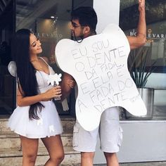 a man and woman standing next to each other in front of a building holding signs